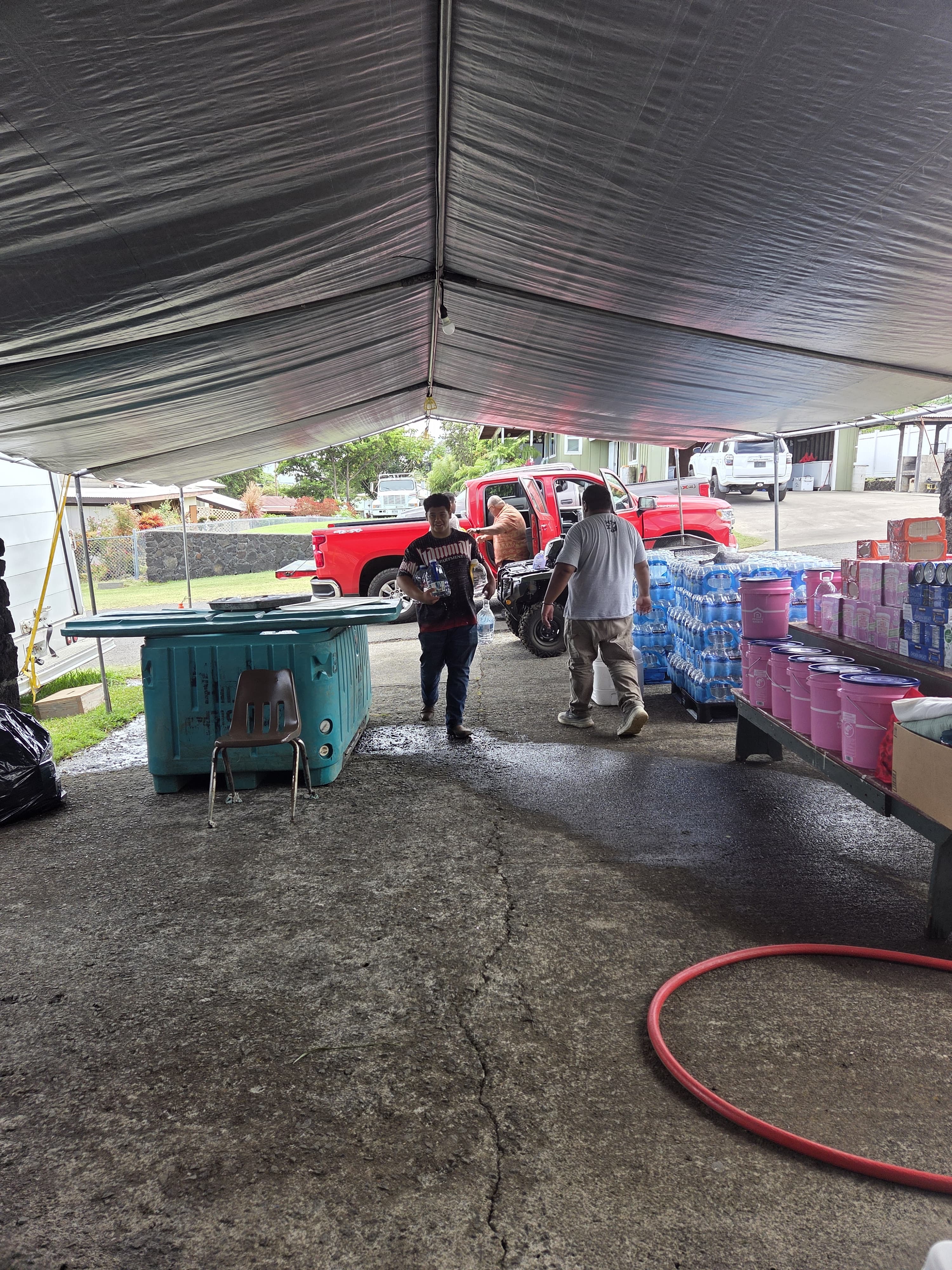 Drinking water being carried into Kaumahana Hub beside emergency supply buckets