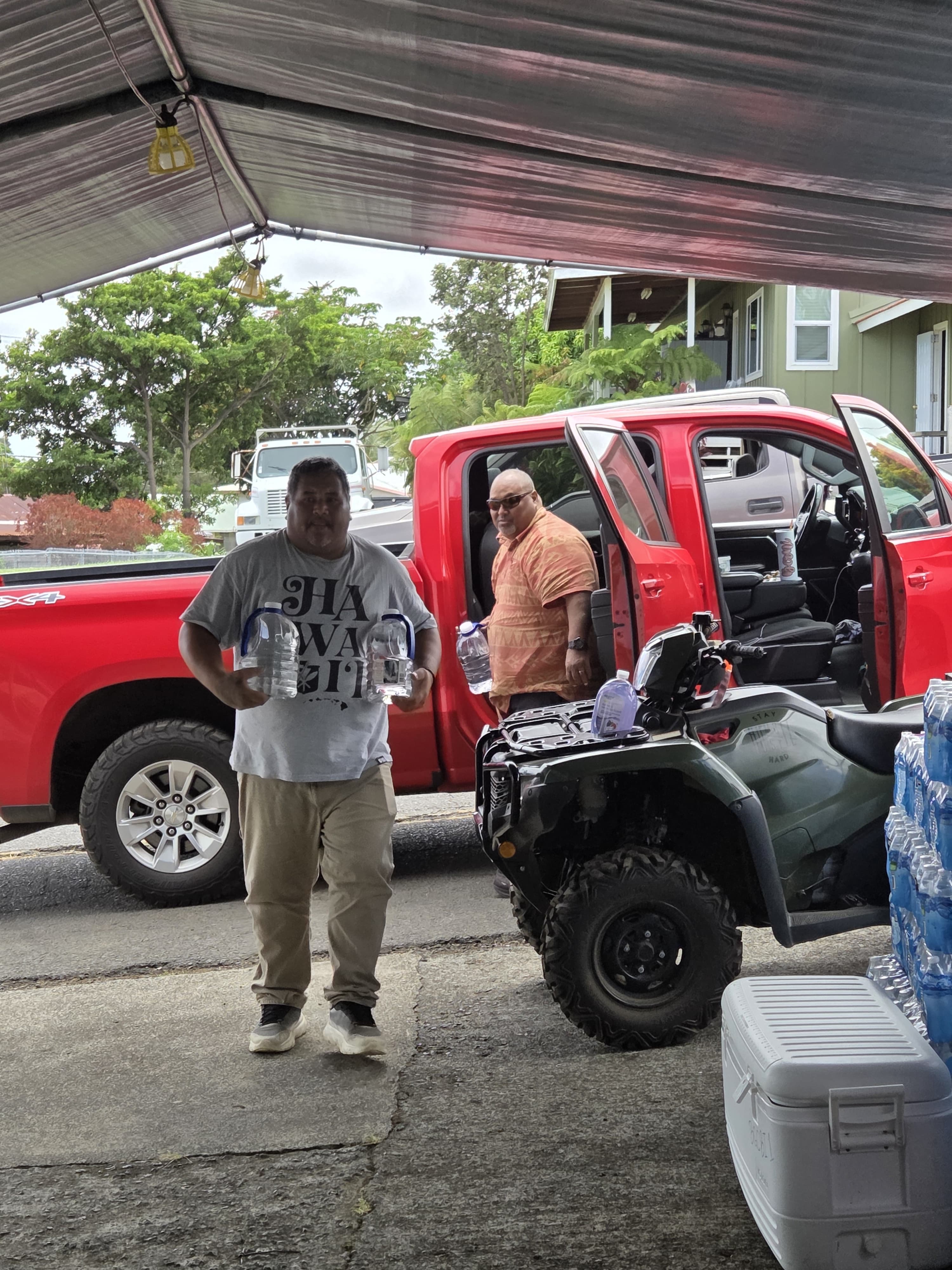 One-gallon bottles of drinking water being unloaded from a red truck