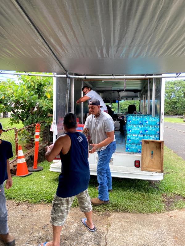 Volunteers unload pallets of water